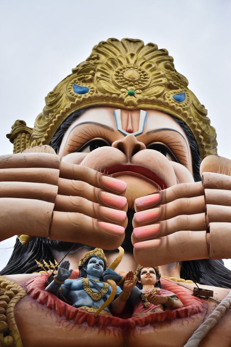 A towering statue of Hanuman with intricate details of Ram and Sita below.