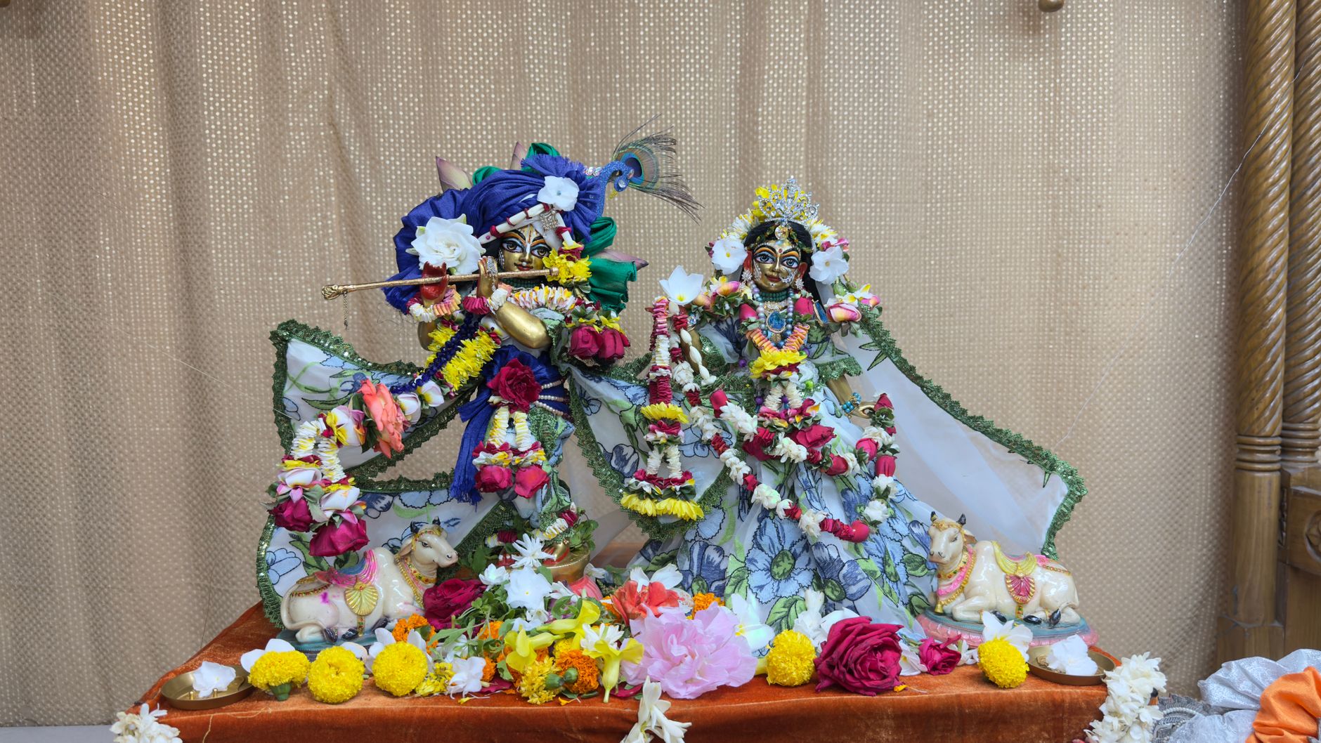 Vibrant statues of Krishna and Radha adorned with flowers, showcasing rich cultural artistry.