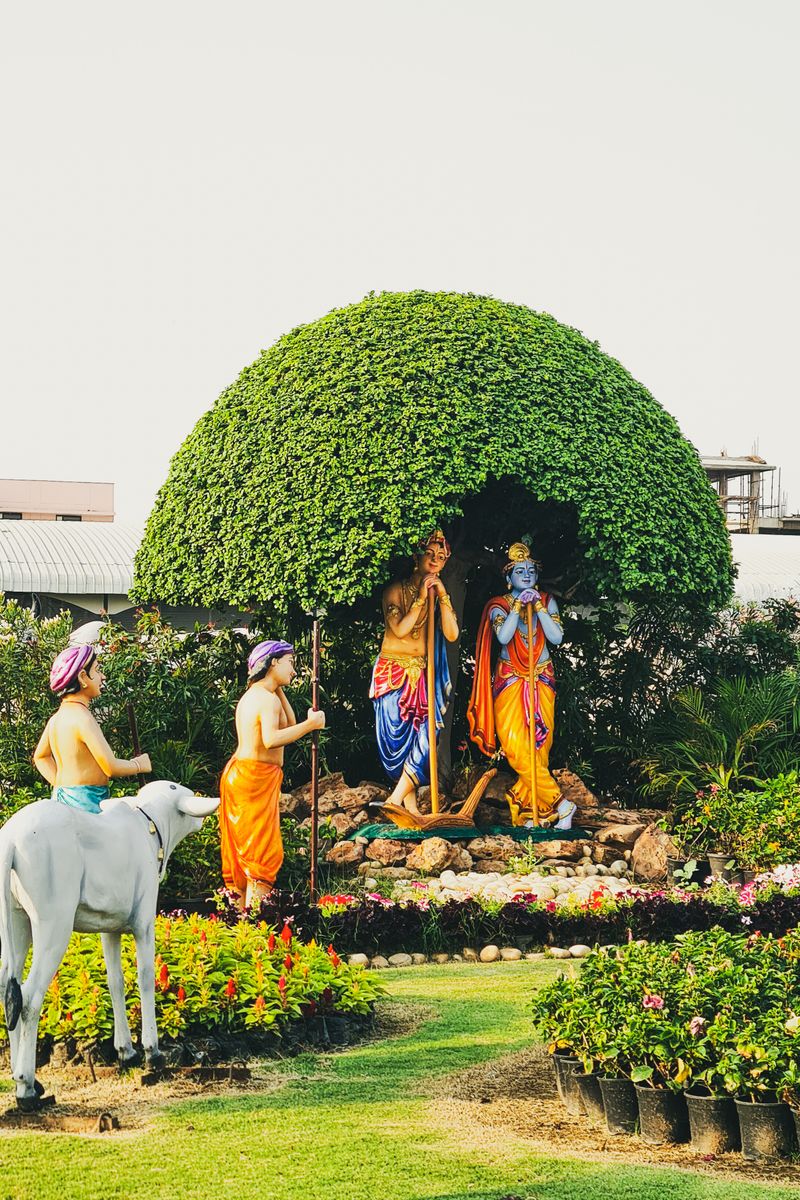 Colorful statues of Lord Krishna in a lush garden in Vrindavan, India.