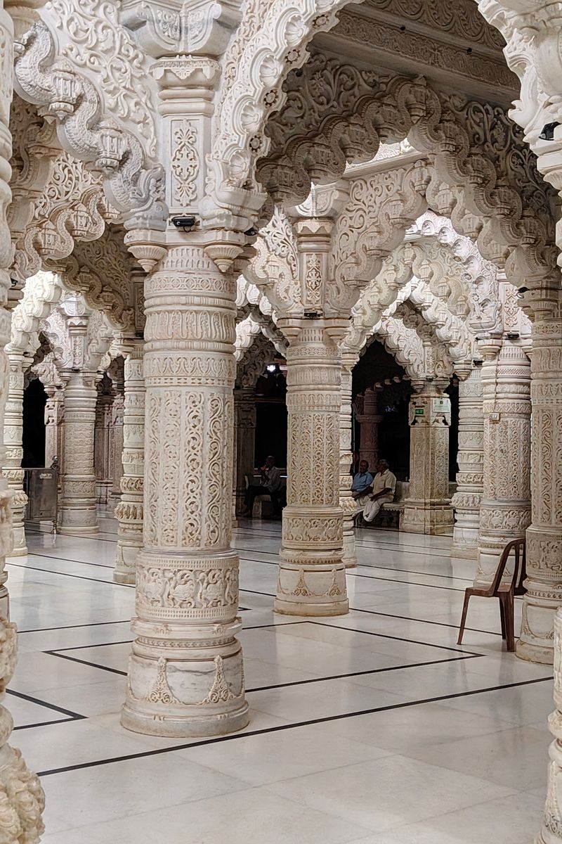 Exquisite carvings and symmetry of a white marble temple with ornate pillars.