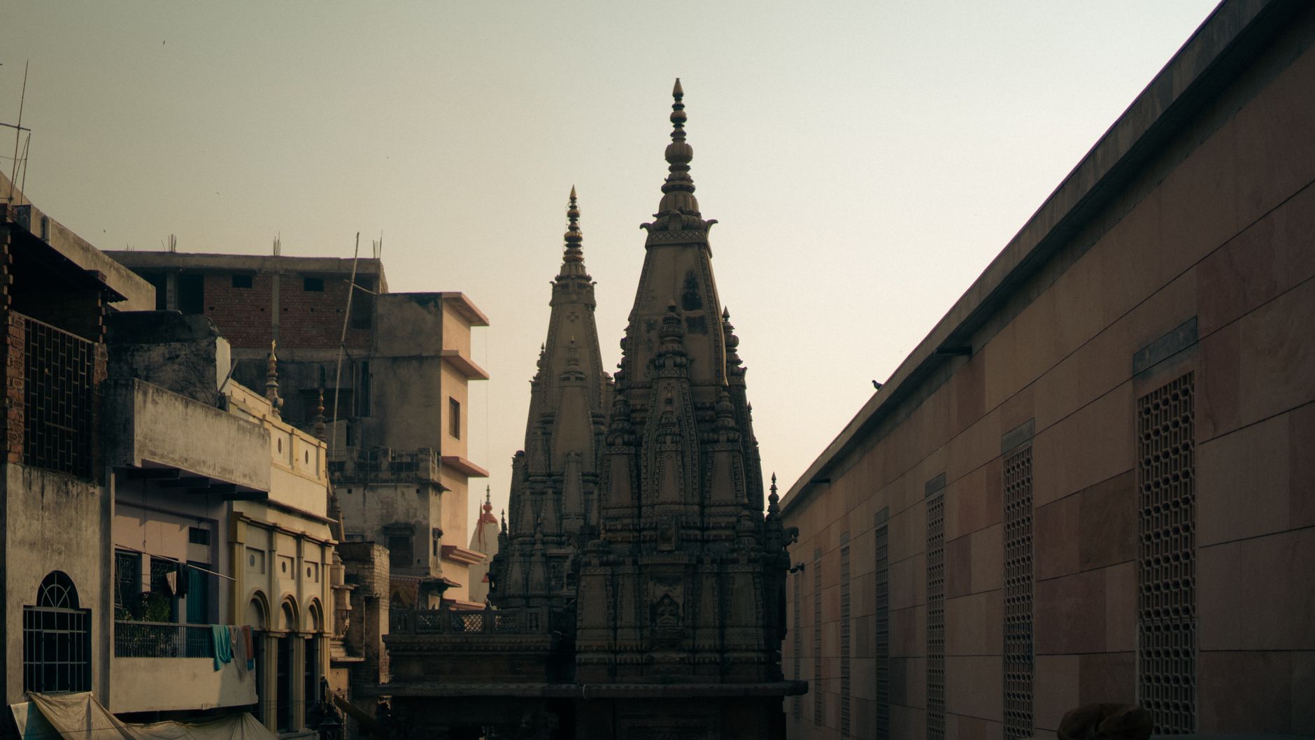 Explore the detailed architecture of a temple nestled among buildings at twilight.