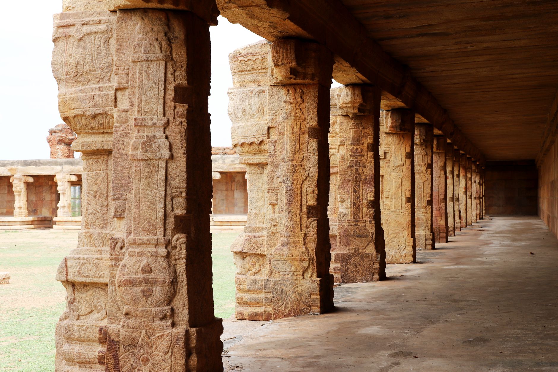 Explore the intricate carvings of a historic temple corridor's ancient stone pillars.